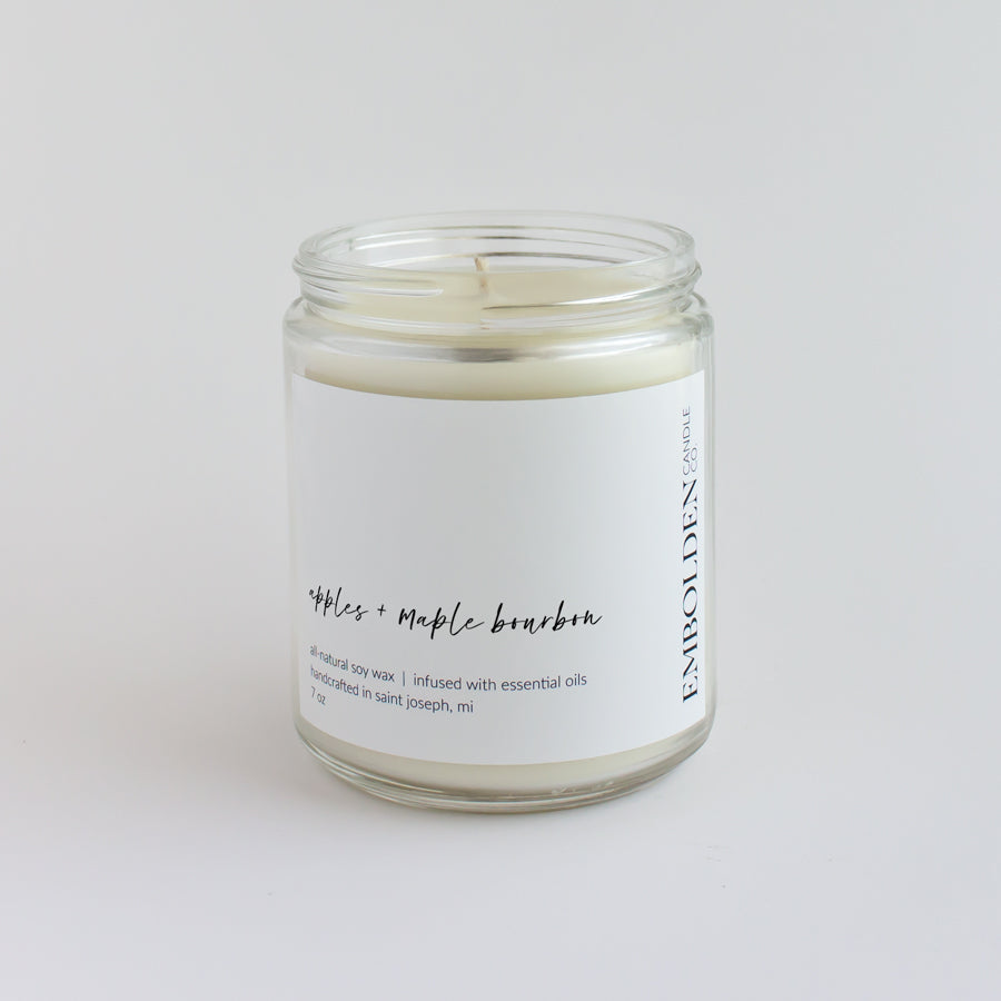 'Apples and Maple Bourbon' scented candle in a clear jar, evoking the warmth and sweetness of fall.