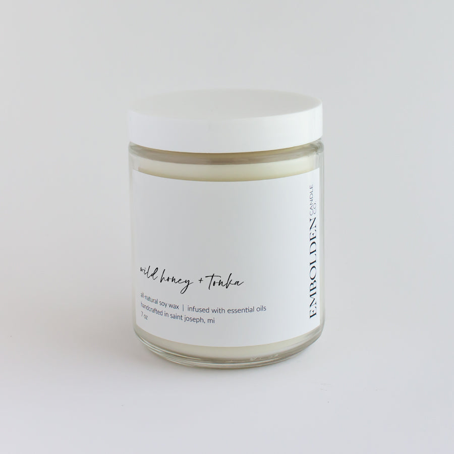 Hand-poured soy wax candle with a sweet wild honey and tonka bean scent in a clear glass jar.