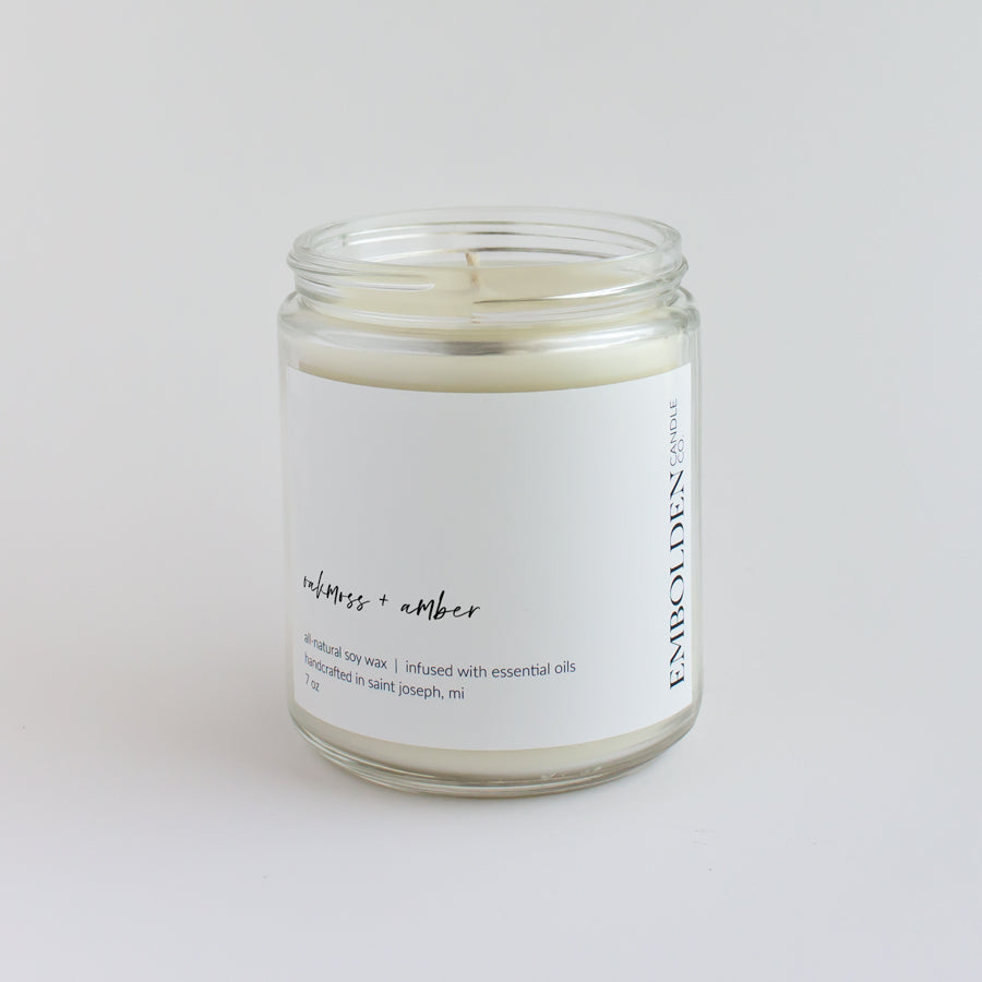 Oakmoss and Amber' candle in a clear jar, bringing earthy comfort to any room.