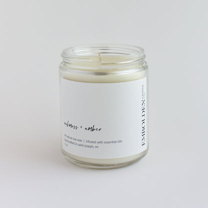 Oakmoss and Amber' candle in a clear jar, bringing earthy comfort to any room.